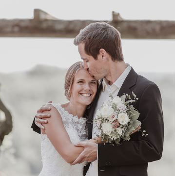 Foto von einem Bräutigam, der seiner Braut einen Kuss auf die Stirn gibt